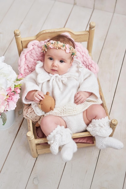 Photo cute baby girl in knitted clothes and wreath children protection day mother's day