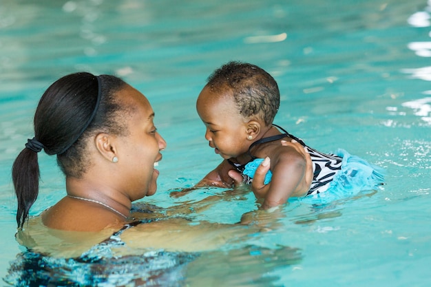 Photo cute baby girl learning how to swim in indoor pool.