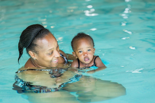 屋内プールで泳ぐ方法を学ぶかわいい女の赤ちゃん。