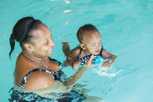 Cute baby girl learning how to swim in indoor pool.