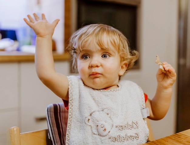 Foto una bambina carina che guarda lontano mentre è seduta su una sedia a casa