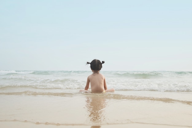 Cute baby girl looking forward to the sea 