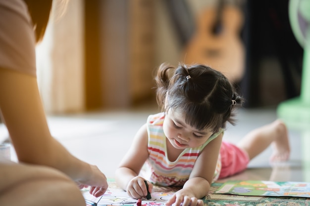 Cute baby girl painting with her mother at the house