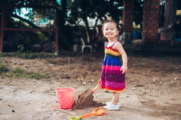 Cute baby girl playing with beach toys cute little girl playing with sand on blur background cute child building sandcastle image about activity of children copy space for text