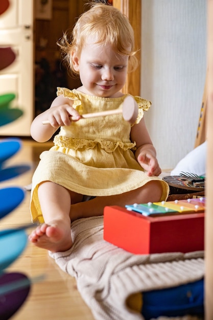 Милая девочка играет на деревянном детском ксилофоне, экологические игрушки, материалы марии монтессори