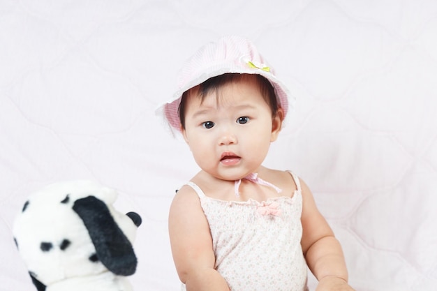 Cute baby girl sitting on bed at home