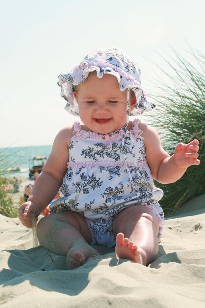 Photo cute baby girl sitting on sand