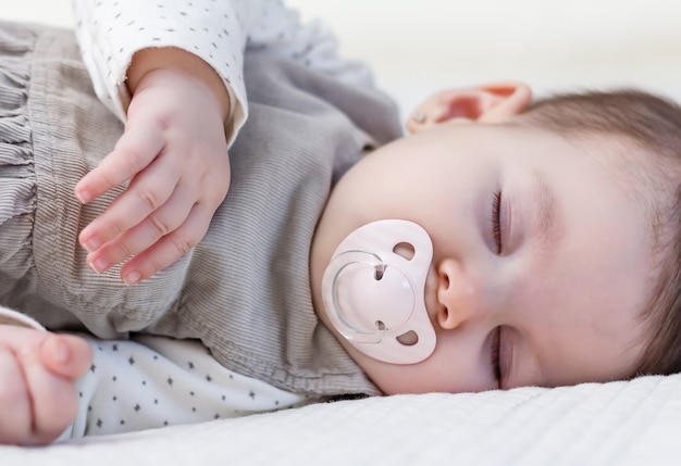 Cute baby girl sleeping over white bedcover