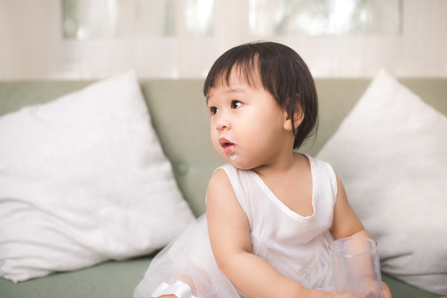 Cute baby girl with milk mustache at home