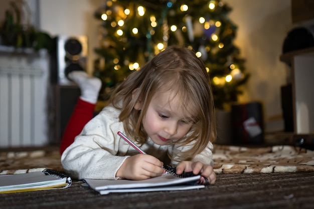 Photo cute baby girl write a letter to santa