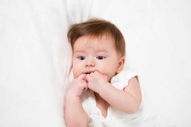 Cute baby has a teething, she gnaws fingers because the first tooth