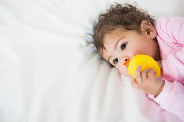 Cute baby holding duck on bed