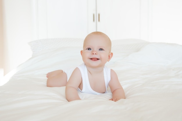 Cute baby is lying on the bed in the bedroom smiling