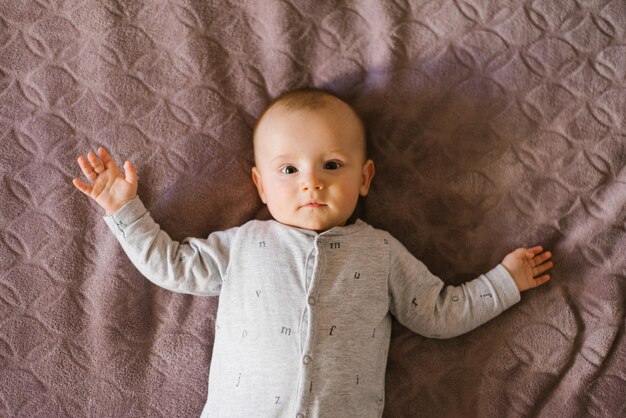 Cute baby is lying on his back on the bed