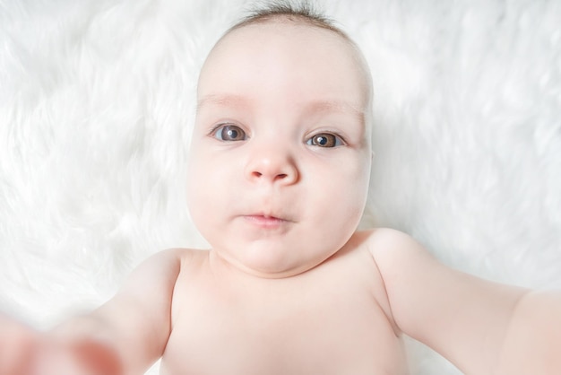 Photo cute baby lies on a white fluffy background
