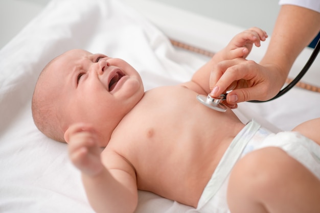 Bambino carino sdraiato sul divano durante l'auscultazione del torace