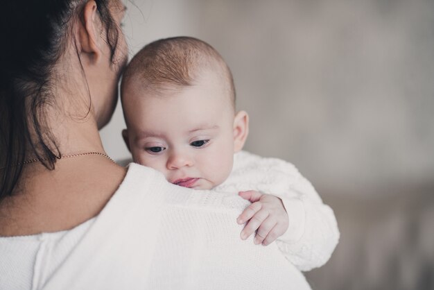 Cute baby under lying on mother hands in room