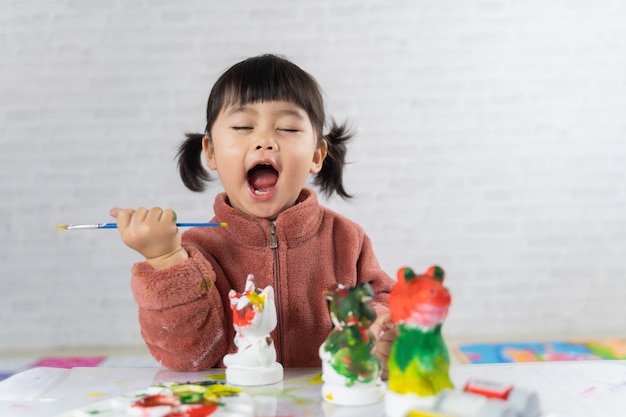 Cute baby painting plaster puppet on the table