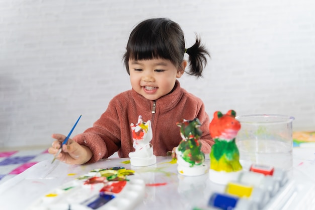 Cute baby painting plaster puppet on the table