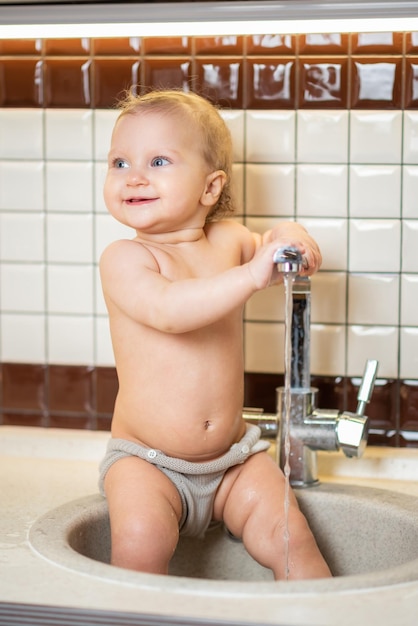 Cute baby playing in the kitchen sink