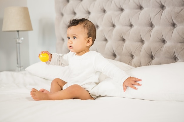 Cute baby playing with ball on bed