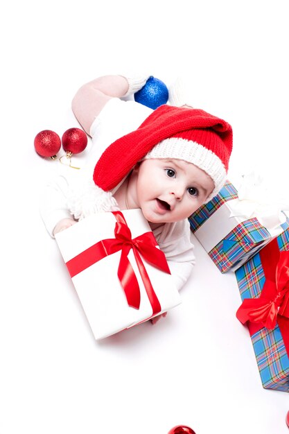 Cute baby in a red New Year's cap with a smile on his face lying