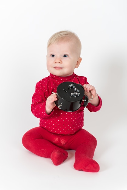 Cute baby in red outfit playing with a clock