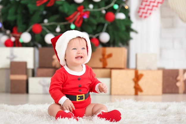 Cute baby in Santa Claus costume at home