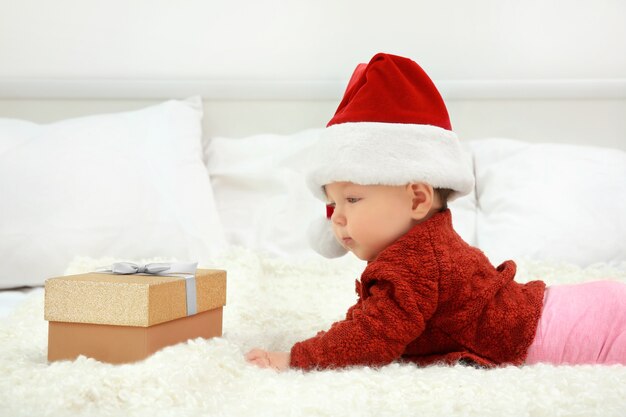 Cute baby in Santa hat on bed