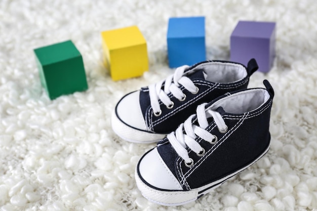 Cute baby shoes and colorful cubes on soft plaid