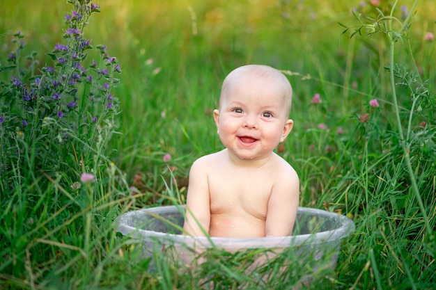 Cute baby sitting in a basin in the grass