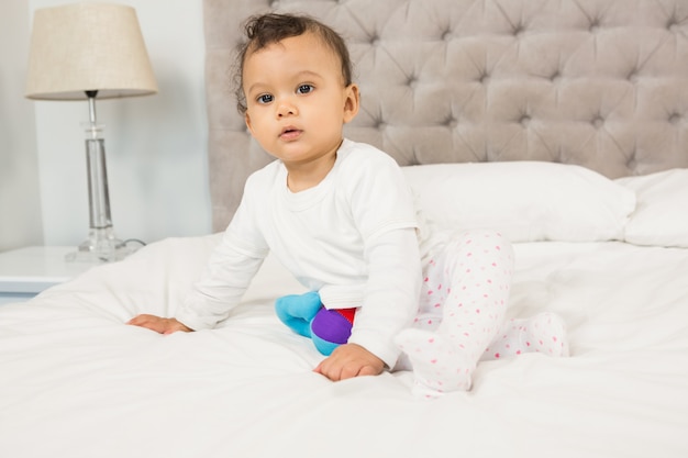 Cute baby sitting on bed looking around