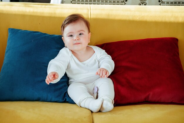 Cute baby sitting on colorful sofa in living room k footage looking at camera