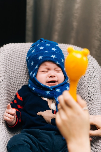 Cute baby sitting and crying in a high chair