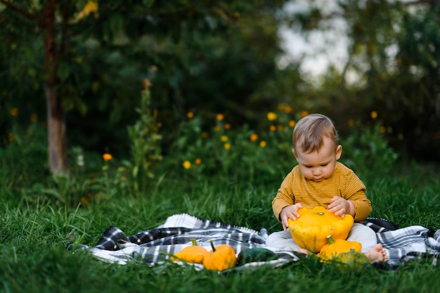 야채 수확과 함께 풀밭에 앉아 있는 귀여운 아기