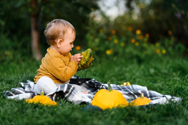 Carino bambino seduto nell'erba con la raccolta delle verdure