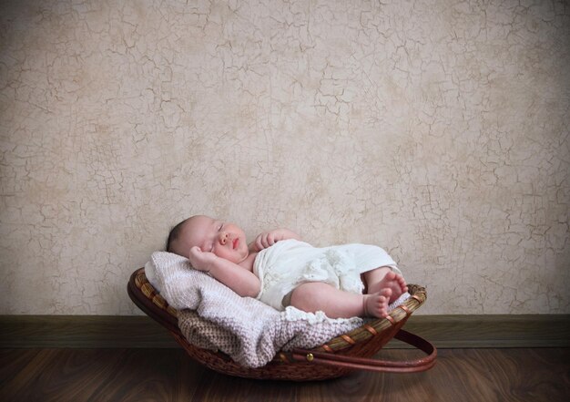 Cute baby sleeping on carrycot at home