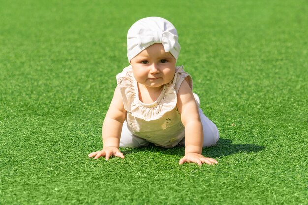 Cute baby toddler crawling, on a green lawn