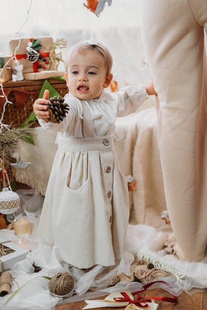 写真 家でおもちゃと花輪を持つクリスマスツリーの近くのかわいい赤ちゃんの幼児の女の子かわいい小さな赤ちゃんの女の子