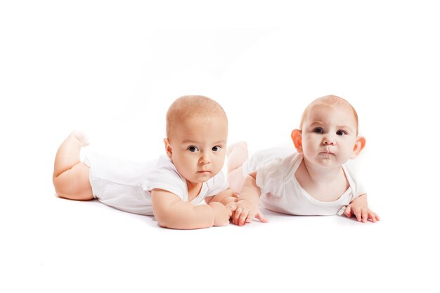 Cute baby twins in white clothes lying