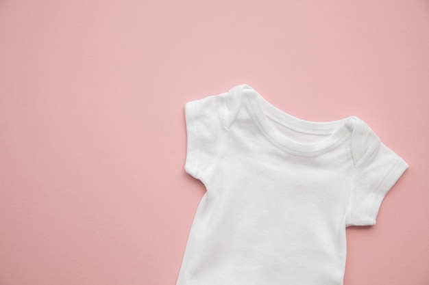 Cute baby white body suit layout on a pastel pink background