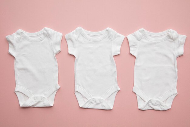 Cute baby white body suit layout on a pastel pink background