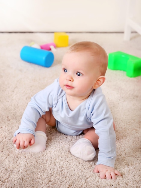 Cute baby with plastic toys on the floor close up