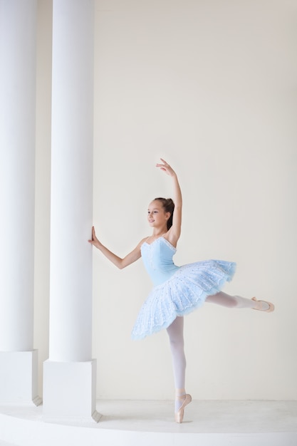 Photo a cute ballerina in ballet costume and in pointe is dancing. girl in the dance class. the girl is studying ballet. ballerina is dancing. beautiful dancer practicing by the mirror.