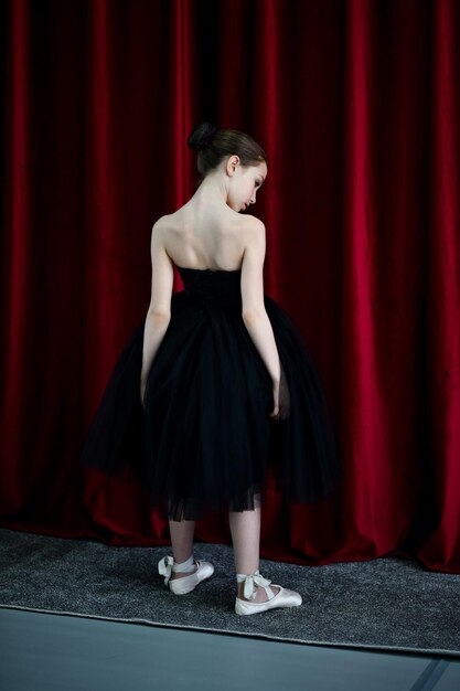 A cute ballerina girl in a black dress on a red background Art Dance Beauty