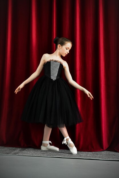 A cute ballerina girl in a black dress on a red background art
dance beauty