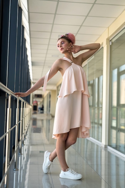 Cute barefoot woman in brown clothes posing inside big business center