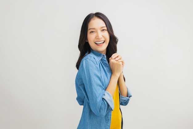 """아름다운 아시아 여성, 긍정적인 미소, 자연스러운, 사랑스러운 태국 소녀, 청바지와 노란 셔츠를 입은 십대, 스튜디오에서 고립되어있다."""