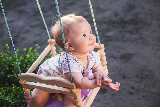 Cute beautiful baby swinging in the yard on a swing sticking