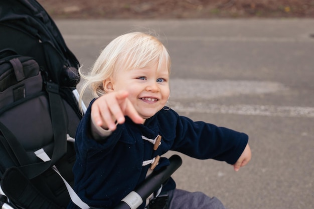 Cute beautiful boy is sitting and smiling in a stroller